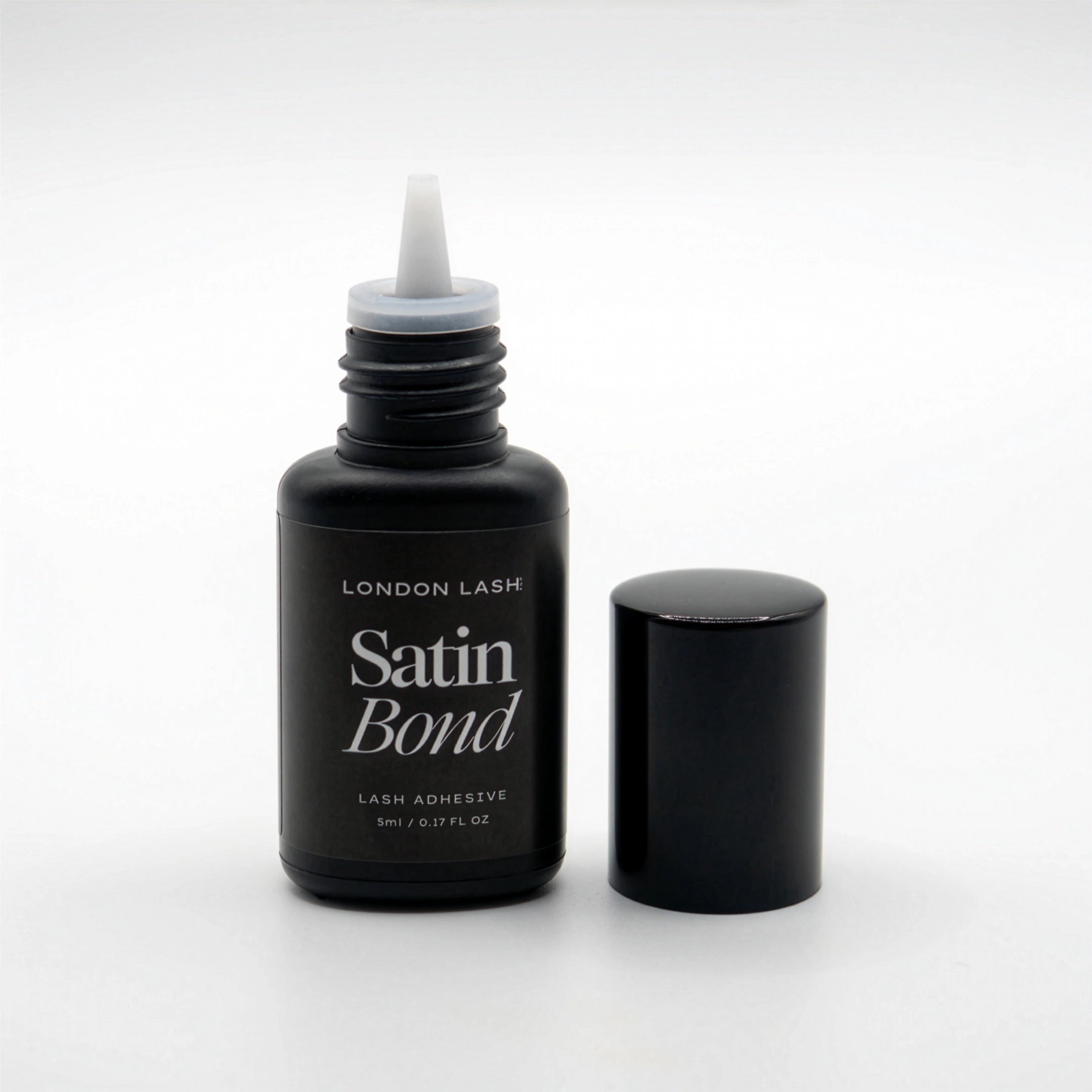 Black bottle of London Lash Satin Bond lash adhesive on a white background