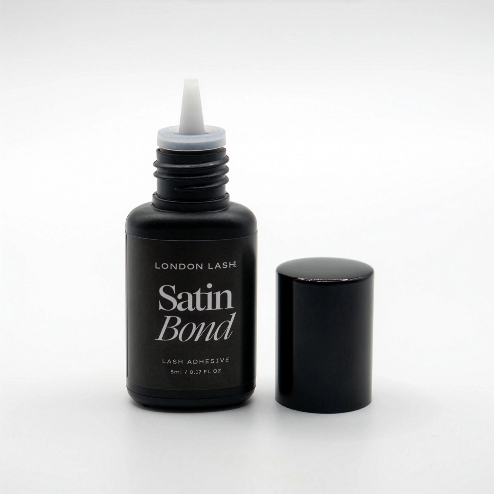 Black bottle of London Lash Satin Bond lash adhesive on a white background